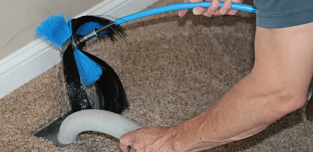 Dryer vent cleaning technician brushing lint from a vent line in Dayton, OH