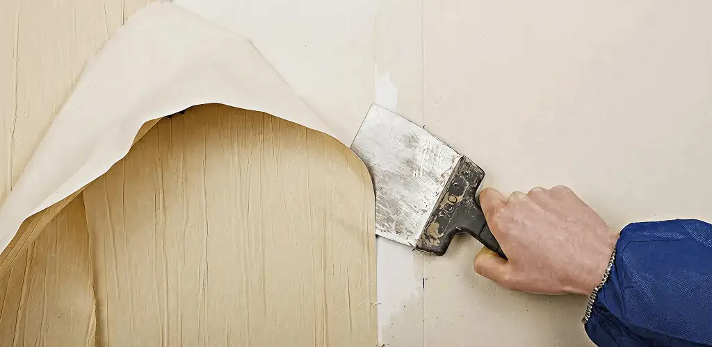 Handyman removing wallpaper with a scraper for wall preparation in Dayton, OH