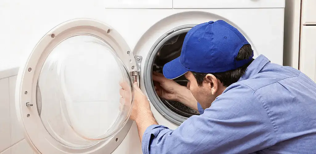 Washing machine repair handyman inspecting a front-load washer drum in Dayton, OH