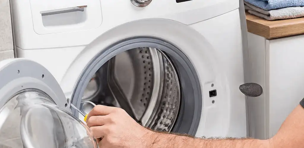 Handyman repairing a front-load washing machine and inspecting the drum in Dayton, OH