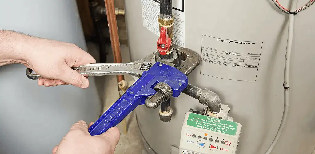 Water heater repair technician tightening the shutoff valve and supply line in Dayton, OH